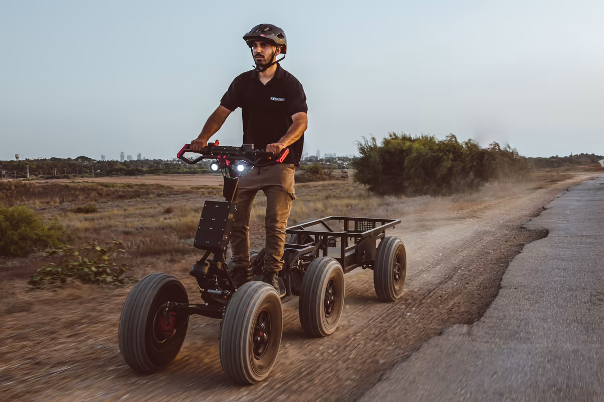Helmeted rider towing an empty EZ Cart beside an open field